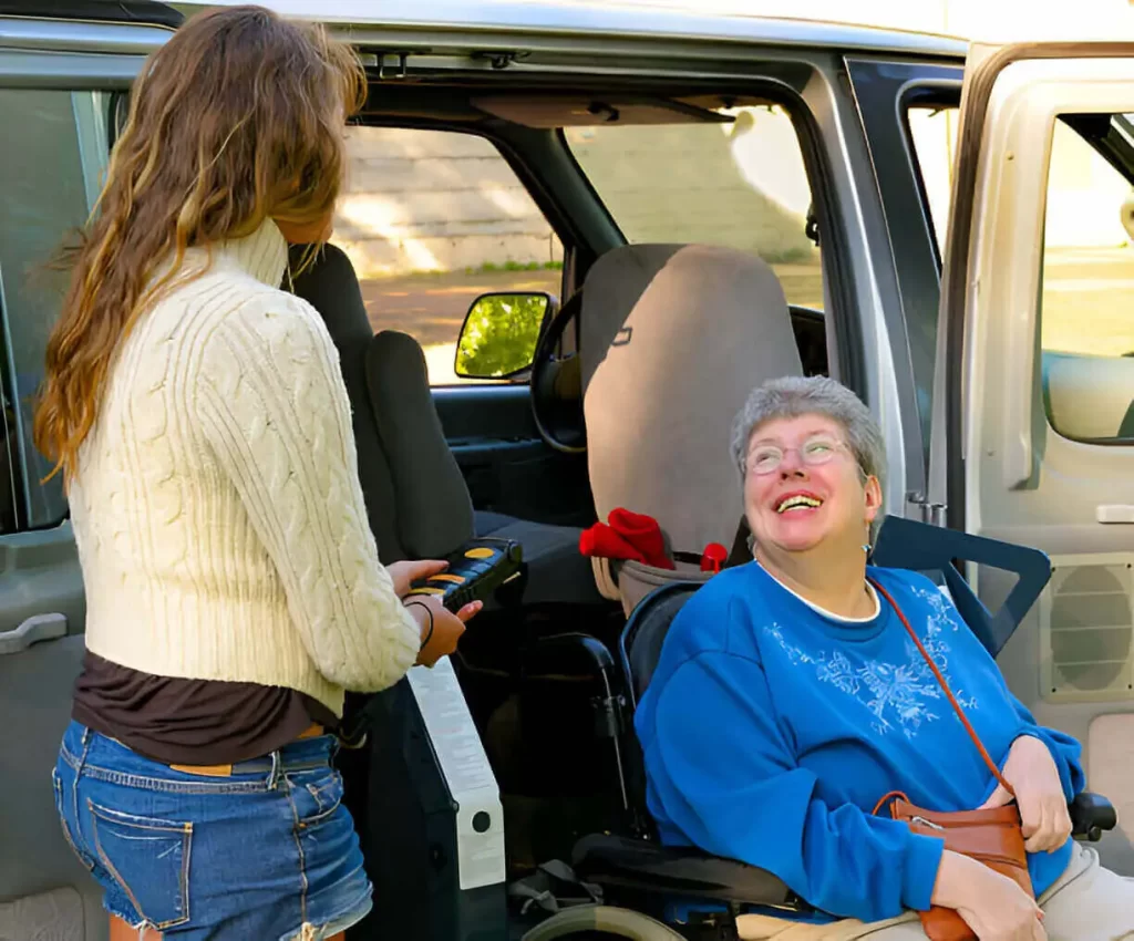 Driver helping elderly woman into wheelchair van in NYC