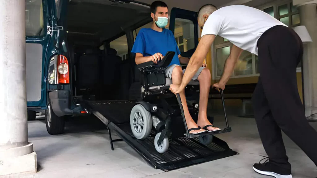 Driver assisting a person in a wheelchair into a lift-equipped shuttle van