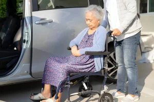 Caregiver assisting senior with wheelchair into ambulette in NYC
